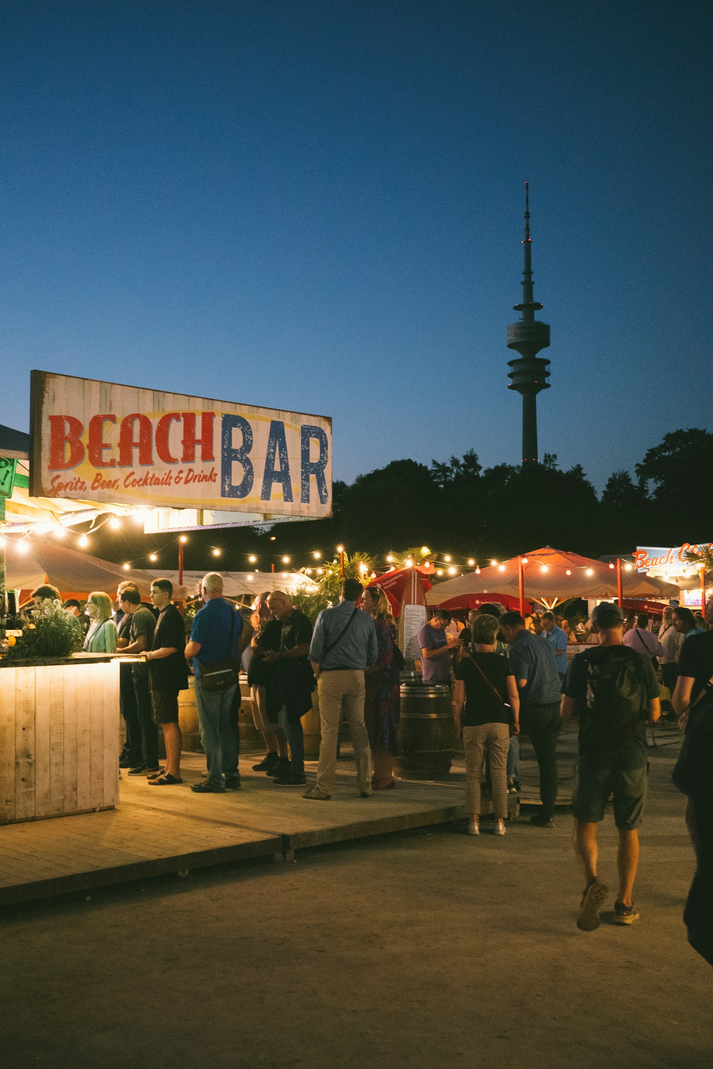 Adults gathering at an outdoor beach bar at dusk
