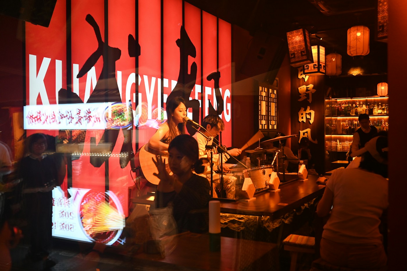 Band performing in a dimly lit bar before a social crowd